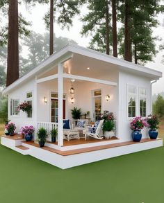 a small white house sitting in the middle of a lush green field next to tall trees