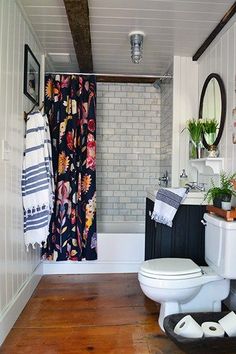 a white toilet sitting in a bathroom next to a bath tub and shower curtain on the wall