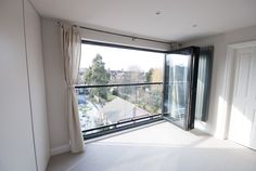 an empty room with sliding glass doors leading to a balcony overlooking a residential area in the background