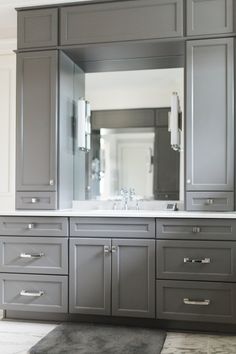 a bathroom with gray cabinets and a large mirror