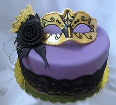 a masquerade cake with purple frosting and black decorations on top is shown