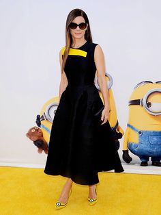 a woman in a black and yellow dress at the despicinte minions movie premiere