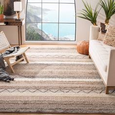 a living room filled with furniture and a large window overlooking the ocean on a sunny day