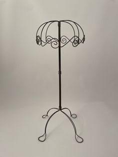 a black metal stand with an umbrella on it's top and two hooks attached to the base