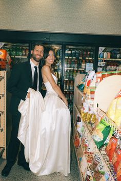 a man and woman standing next to each other in front of a grocery store display