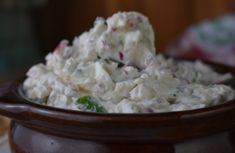 a wooden bowl filled with potato salad on top of a table