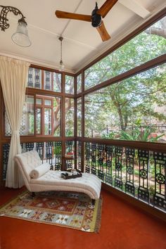 a living room with a ceiling fan and large windows