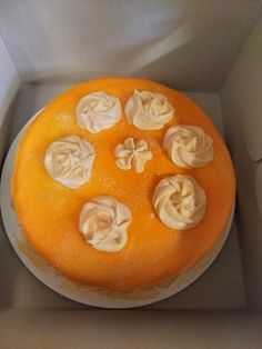 an orange cake with white frosting in a box