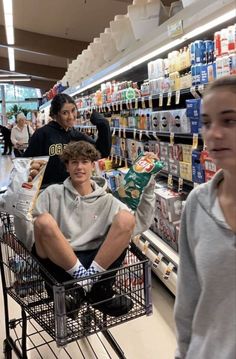 two boys sitting in a shopping cart at the grocery store