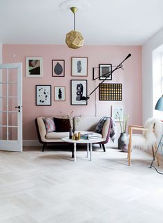 a living room with pink walls and pictures on the wall