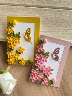 two greeting cards with flowers and butterflies on them, one is yellow and the other is pink