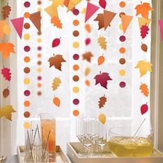 a table topped with glasses filled with drinks next to a window covered in fall leaves