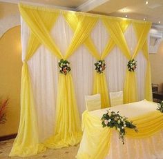 a banquet table with yellow drapes and flowers on it