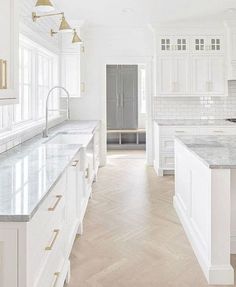 a large kitchen with white cabinets and marble counter tops, along with an island in the middle