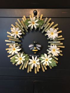 a wreath made out of sticks and flowers with a bee sitting on the center piece