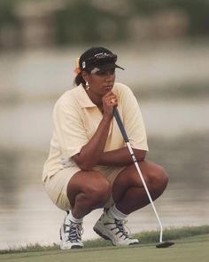 a woman kneeling down to put her golf ball on the green