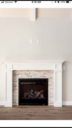 an empty living room with a fireplace and white paint on the walls, wood flooring