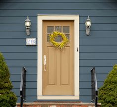 a yellow wreath on the front door of a blue house