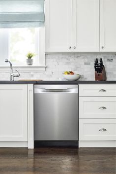 a kitchen with white cabinets and stainless steel dishwasher