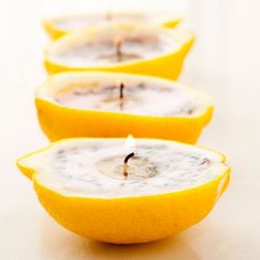 three lemon halves with a candle in the middle on a white table top, one half cut open