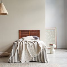 a bed sitting in a bedroom next to a lamp on a wooden headboard and pillow