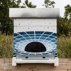 a white and blue stove sitting on top of a wooden table next to tall grass