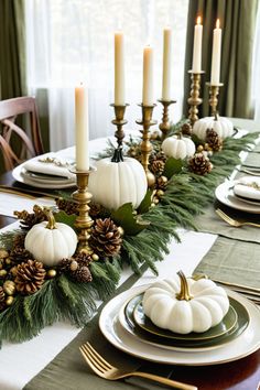 a table set with white pumpkins, pine cones and greenery