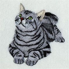 a gray and black cat with green eyes on a white background embroidered onto a piece of cloth