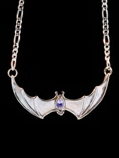 "This solid sterling silver Bat pendant would love to hang around your neck. It's wing span is 2 1/4\" across. A 16\" figaro chain is attached to both wing tips and is included in the price of this piece making the total length of the pendant just over 18\". A 5mm x 7mm gemstone is bezel set in the back of the bat. Take flight with one tonight. Please select your desired gemstone in the dropdown options menu. You may choose between a Blue Topaz, Citrine, Amethyst, Peridot, Black Onyx or Mozambiq Gothic Winged Jewelry For Gifts, Gothic Winged Jewelry Gift, Gothic Gemstone Jewelry For Collectors, Gothic Sterling Silver Jewelry With Polished Finish, Gothic Collectible Gemstone Jewelry, Gothic Sterling Silver Jewelry, Collectible Gothic Gemstone Jewelry, Silver Winged Engraved Jewelry, Engraved Winged Sterling Silver Jewelry