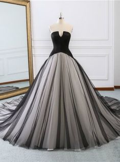 a black and grey ball gown on display in front of a mirror with a gold frame