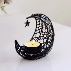 a black candle holder with a crescent and star on the top, sitting on a white table