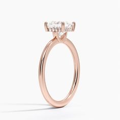 a rose gold engagement ring with two stones on the top and side, set against a white background