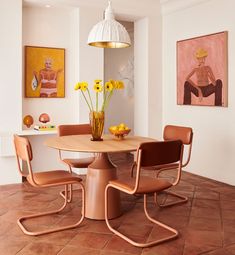 a dining room table and chairs with yellow flowers in vases on the end tables