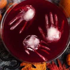 two hands made out of ice on top of a glass bowl filled with red liquid