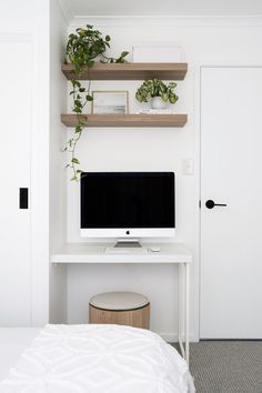 a white desk with a computer on it and some plants in front of the monitor