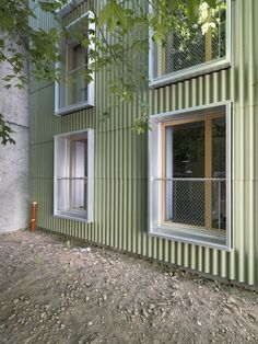 an exterior view of a green building with two windows