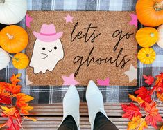 a person standing in front of a door mat that says let's go ghouls