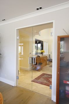 an open door leading to a living room and dining room with wood flooring on the other side