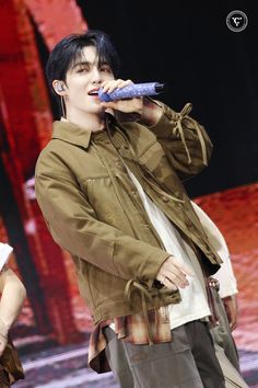 a male in a brown jacket is holding a microphone