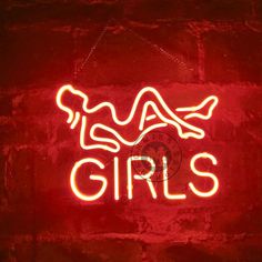 a neon sign that says girls on it in front of a brick wall with a clock