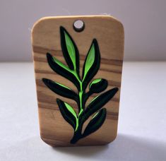 a wooden plaque with green leaves on it's side and a tag attached to the back