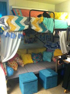 a room with bunk beds and colorful pillows on the bed, along with blue stools