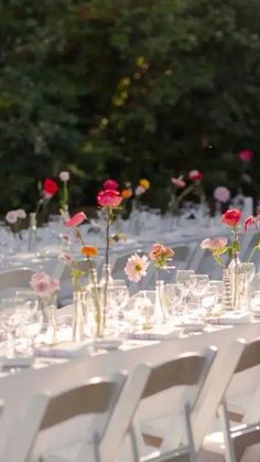 a long table is set up with flowers and wine glasses for an outdoor wedding reception