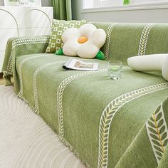 a green couch with a white flower on top of it and a glass next to it