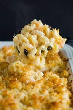 a spoon full of macaroni and cheese being lifted from a casserole dish