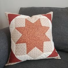 a red and white pillow sitting on top of a gray couch