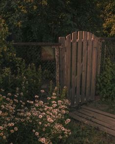 a wooden gate in the middle of some flowers