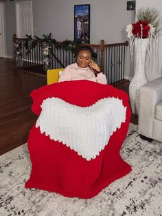 a woman sitting in a chair with a blanket on top of her and she is talking on the phone