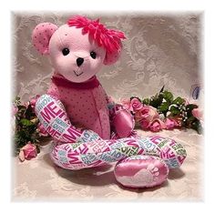 a pink teddy bear sitting on top of a table next to some flowers and greenery