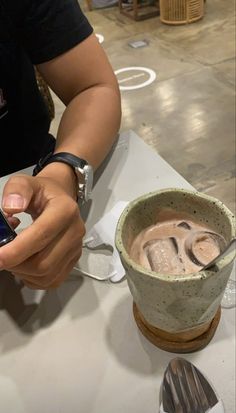 a person sitting at a table holding a cell phone in their hand and looking at the screen